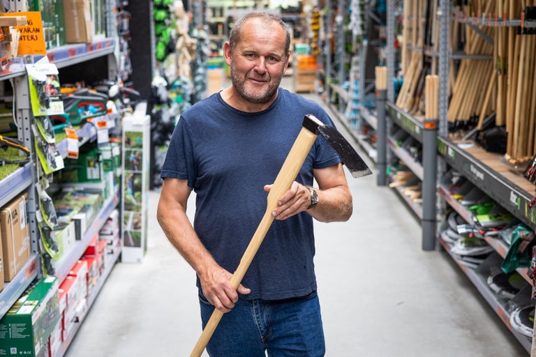 En man håller en hacka i en Hornbach-butik.