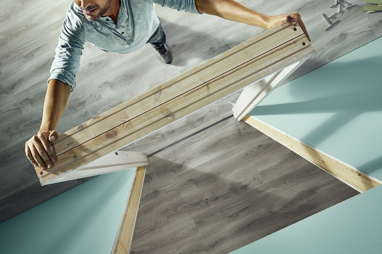Man monterar träkonstruktion på grått golv
