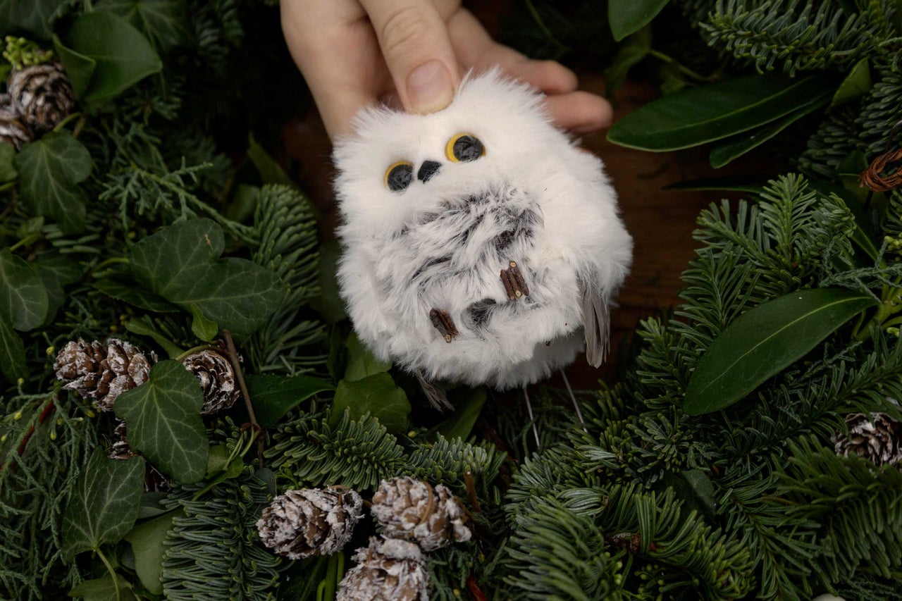 Dekorativ snöuggla av filt med grangrenar och kottar