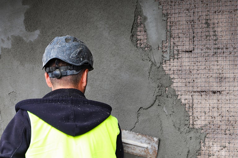 Hantverkare applicerar fasadputs med armeringsväv