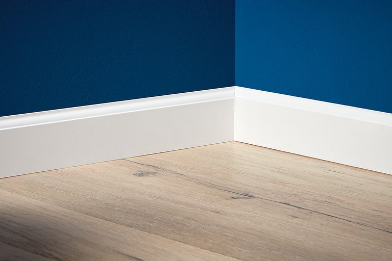 Hörn av ett rum med vita golvlister och laminatgolv