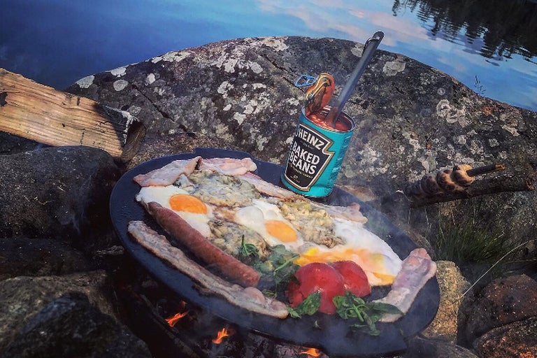 Frukost med ägg, bacon, korv, tomater och bönor tillagad i naturen.