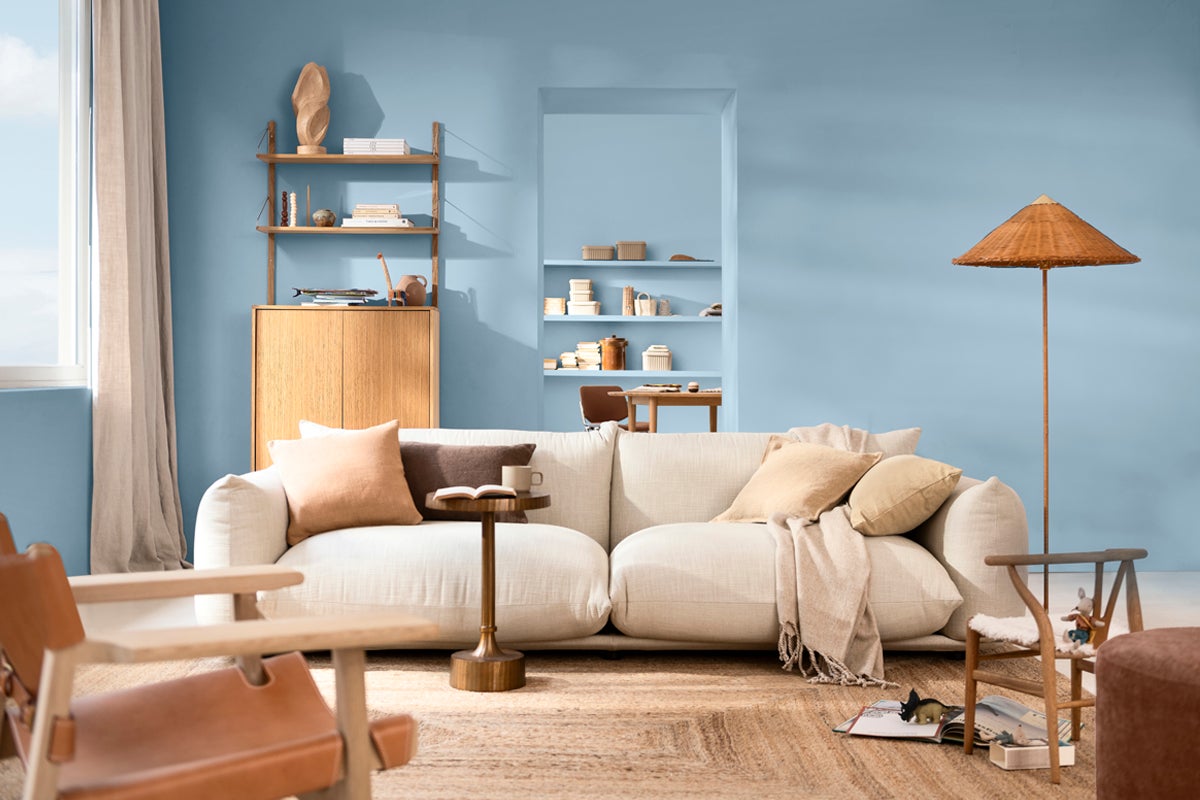 Vardagsrum med soffa, hyllor och dekorationer i ljusa färger.