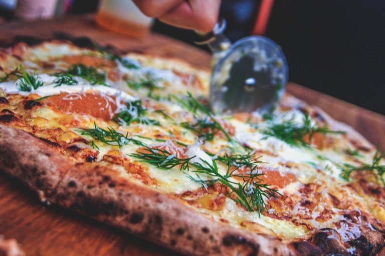 Pizza skärs med en pizzaskärare.