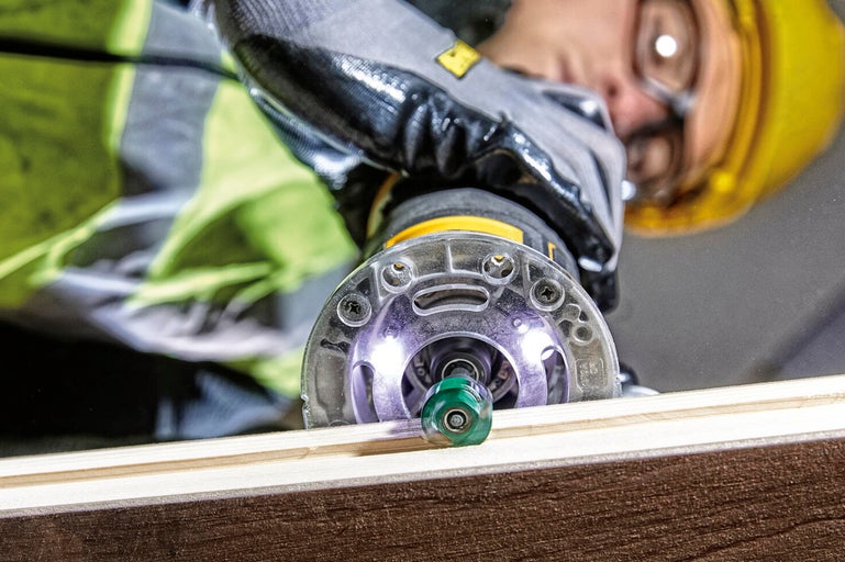 Hantverkare använder en handöverfräs på en träplanka