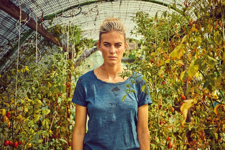 Kvinna står i ett växthus med tomatplantor