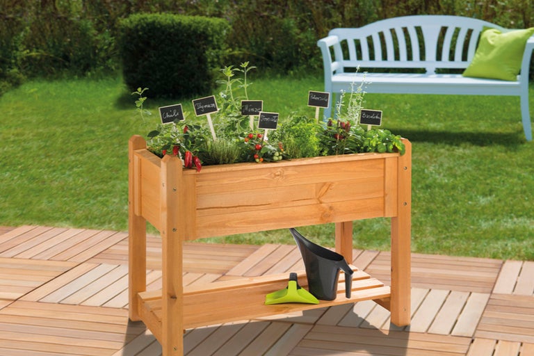Hög träbädd med örter och trädgårdstillbehör