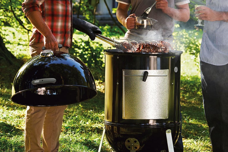 Personer grillar med en Weber Smokey Mountain Cooker -rök utomhus