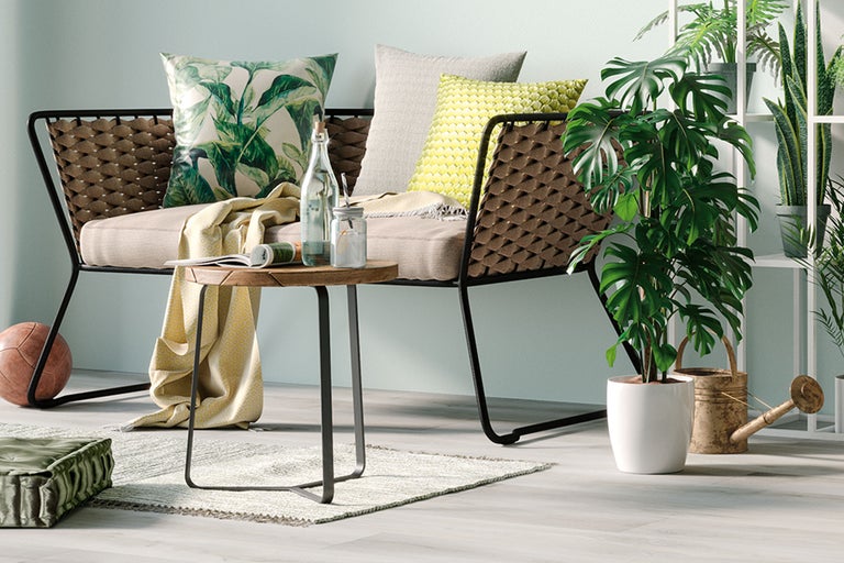 Vardagsrumsscen med soffa, bord, kuddar och krukväxter