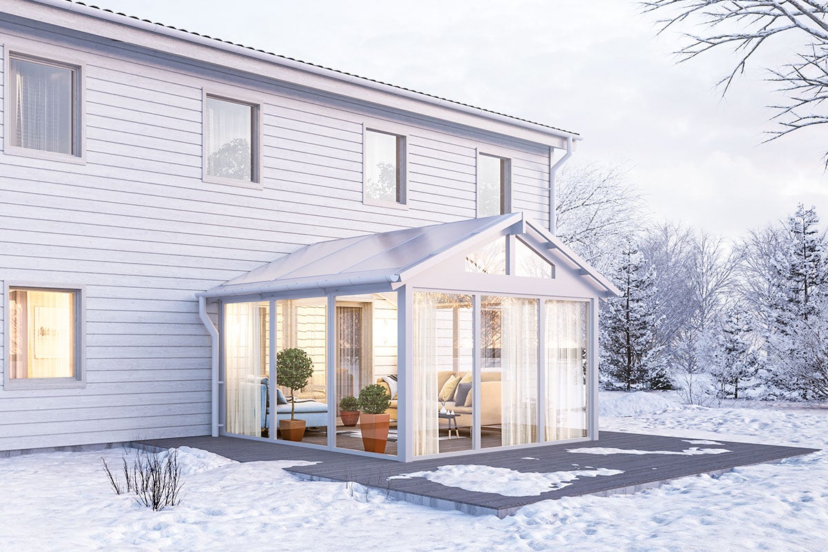 Vinterträdgårdsförlängning till ett hus med fönster och terrass i snön