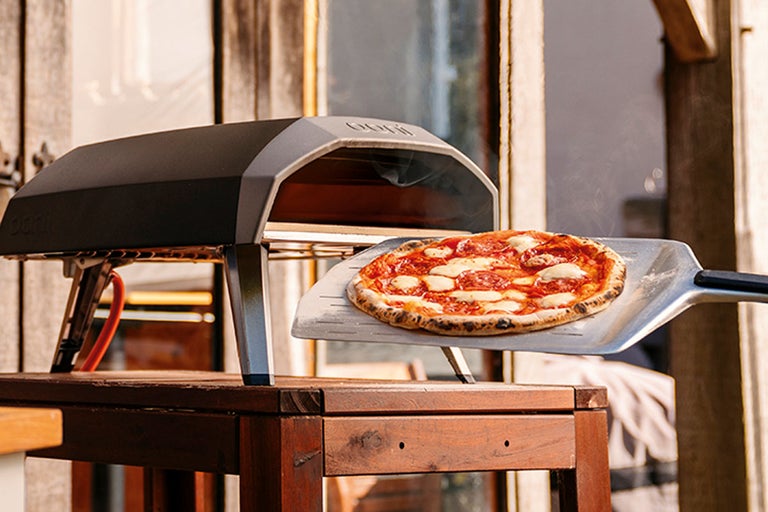 Ooni pizzaugn med pizza på pizzaspade på träbord