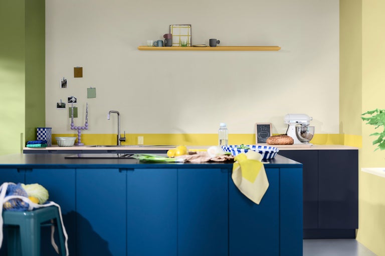 Ljust kök med köksö, diskho, blandare, köksmaskin och vägghylla