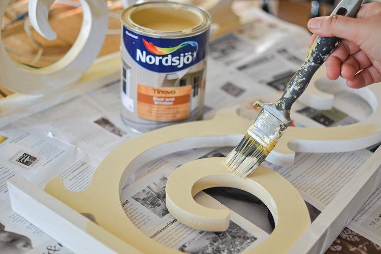 Målning av ett trädekorationselement med pensel och Nordsjö färg för dörrar och fönster