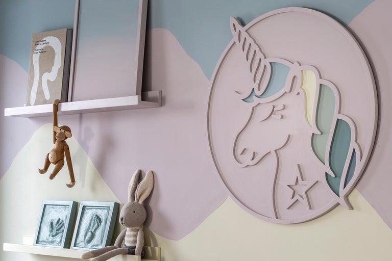 Dekorativt barnrum med enhörningsväggmålning, hyllor och leksaker