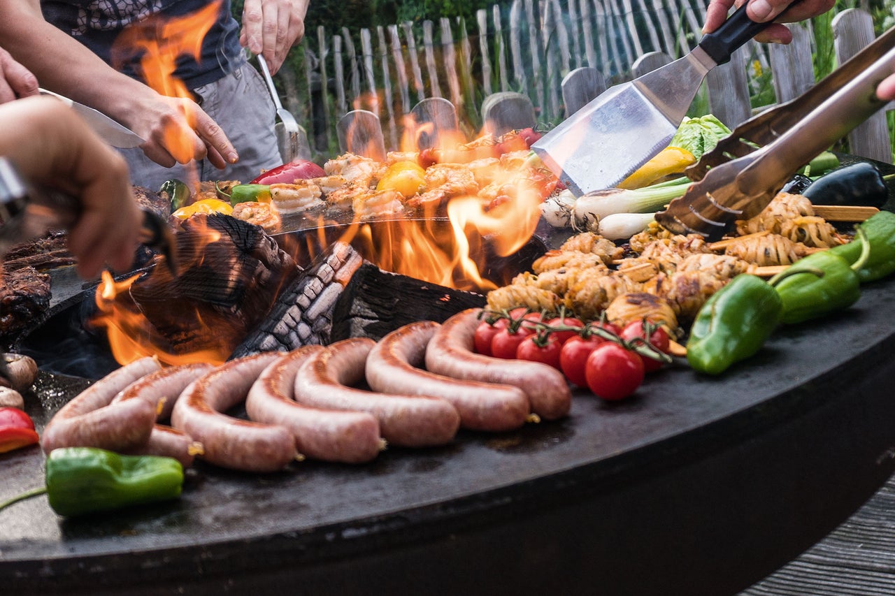 Grillscen med korv, grönsaker och kött tillagat över eld