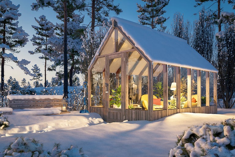 Vinterscen med ett växthus av trä och glas i en snötäckt trädgård.