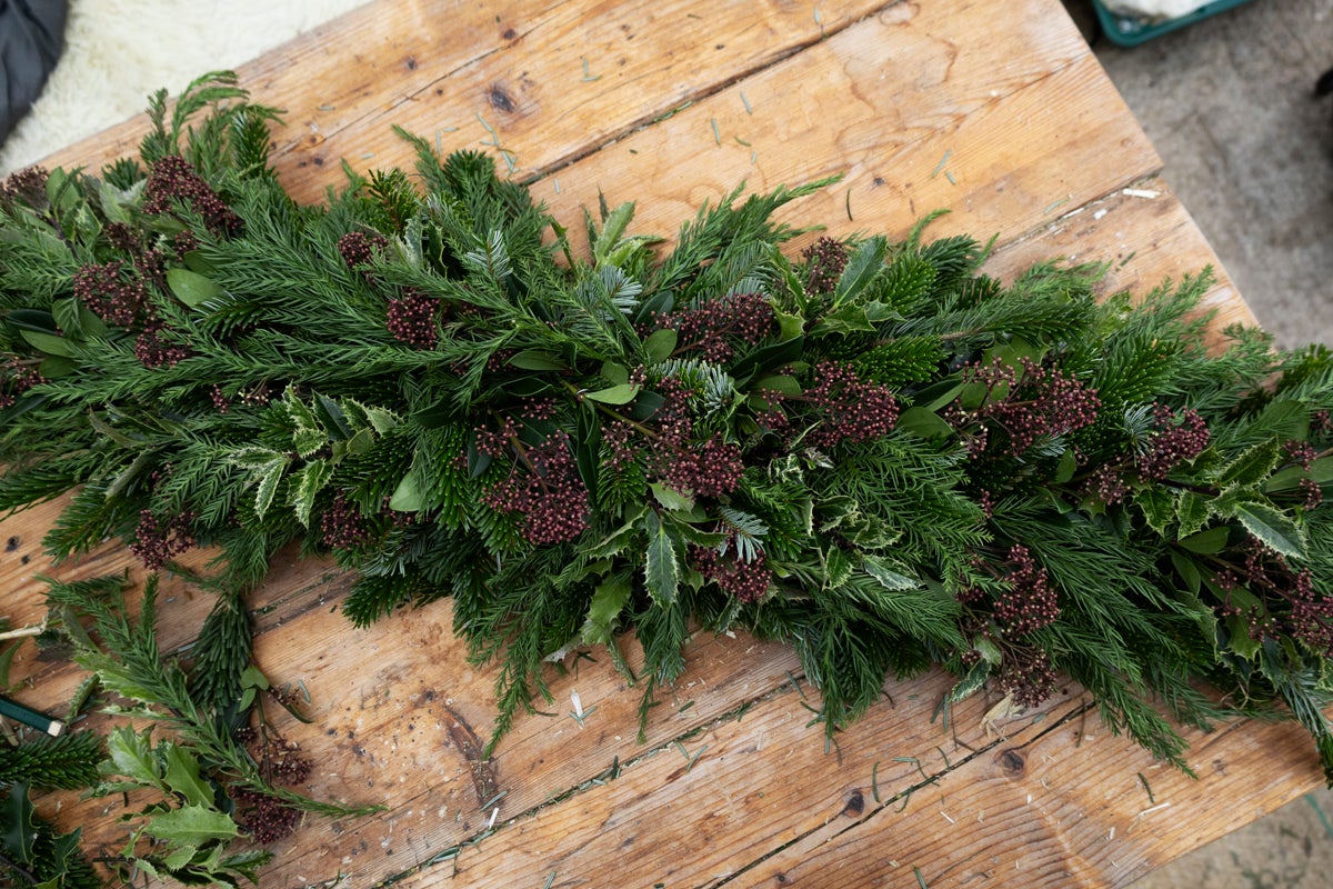 Festlig julbordslöpare med grangrönt, järneksblad och bär på träbord