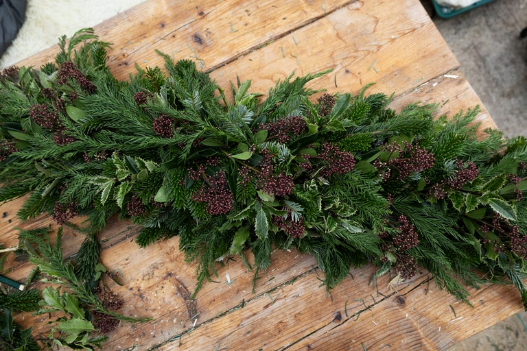 Festlig julbordslöpare med grangrönt, järneksblad och bär på träbord