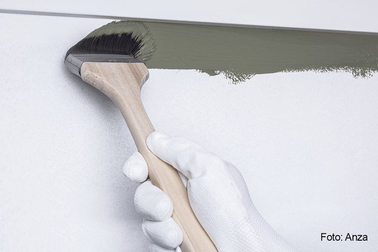 En person målar en vägg med en pensel.