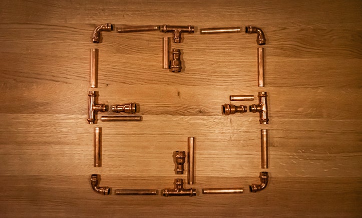 Fyrkant av kopparrör och kopplingar på träunderlag