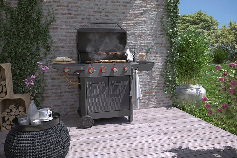 Gasolgrill på en terrass med en tegelvägg och växter