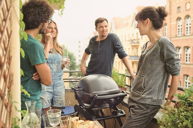 Folk grillar på balkongen med en elektrisk grill och njuter av tiden tillsammans.