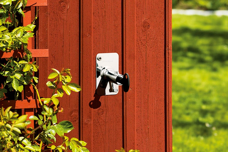 Vattenkran i metall för trädgårdsbevattning på en trävägg