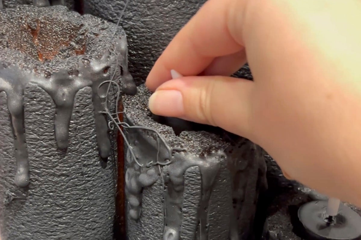 Dekorativa, svarta ljus med droppande vaxdesign och hand som placerar ett ljus.