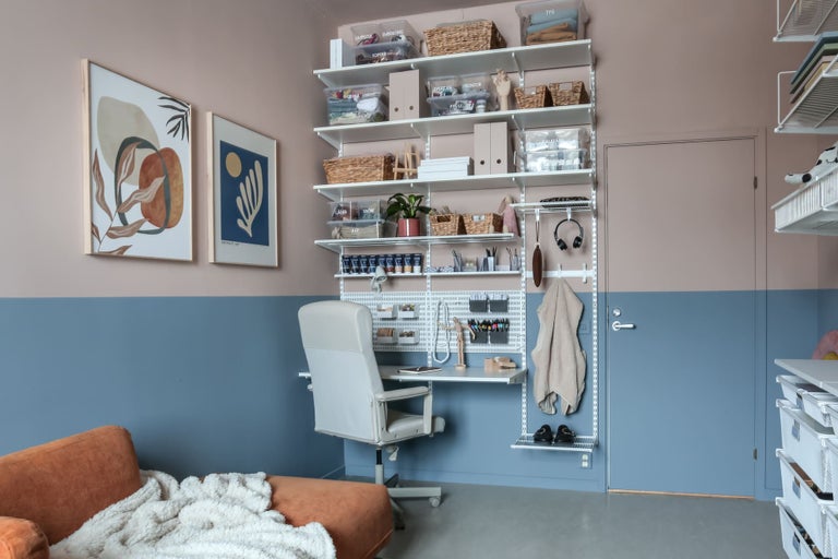 Kontor med hyllsystem, skrivbord, kontorsstol och soffa i ett rum