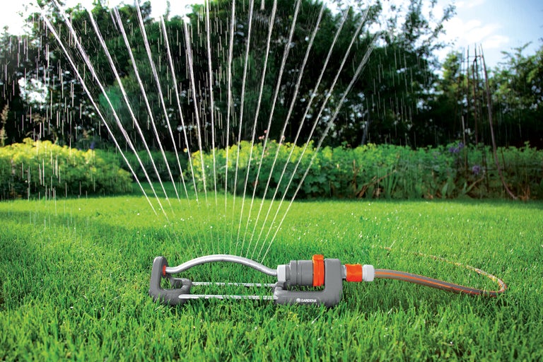 Vattenspridare som vattnar en grön gräsmatta
