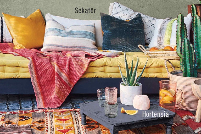 Dekorativ scen med kuddar, filtar, bord och växter för inredningsdesign