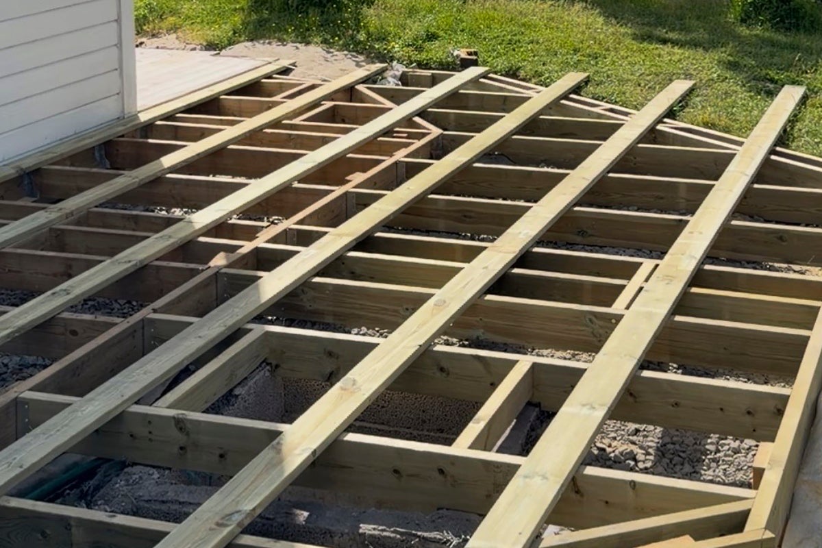 Bygge av en träterrass med en underkonstruktion av träbalkar på en grusbädd utomhus.