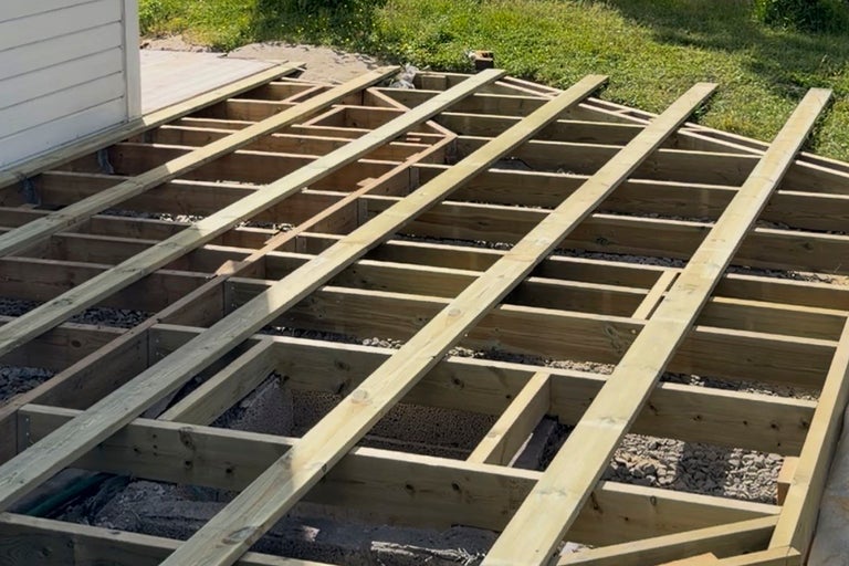 Bygge av en träterrass med en underkonstruktion av träbalkar på en grusbädd utomhus.
