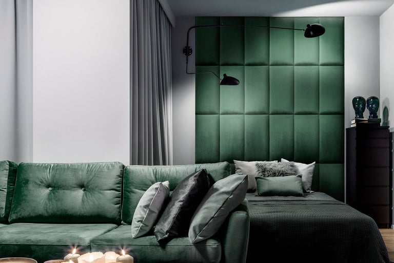 Ljust rum med soffa, säng, väggpaneler, gardiner och dekoration