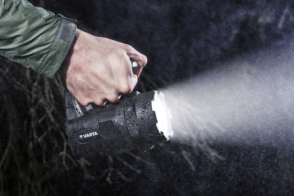 En person håller en Varta handlampa i regnet.