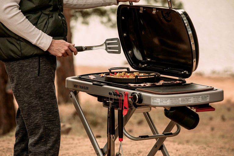 Weber Traveler gasolgrill med grillad mat och person