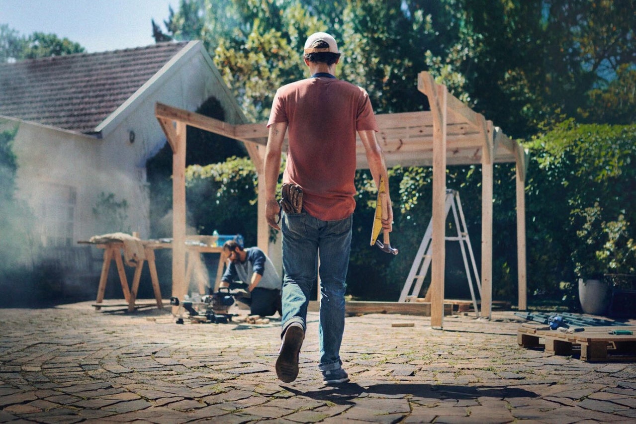 Två hantverkare bygger en träkonstruktion utomhus.