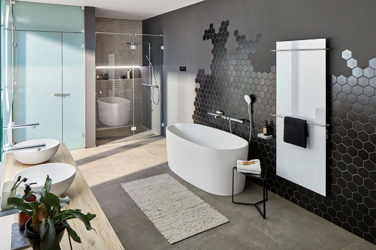 Ljust badrum med fristående badkar, dusch, två handfat och sexkantiga väggplattor