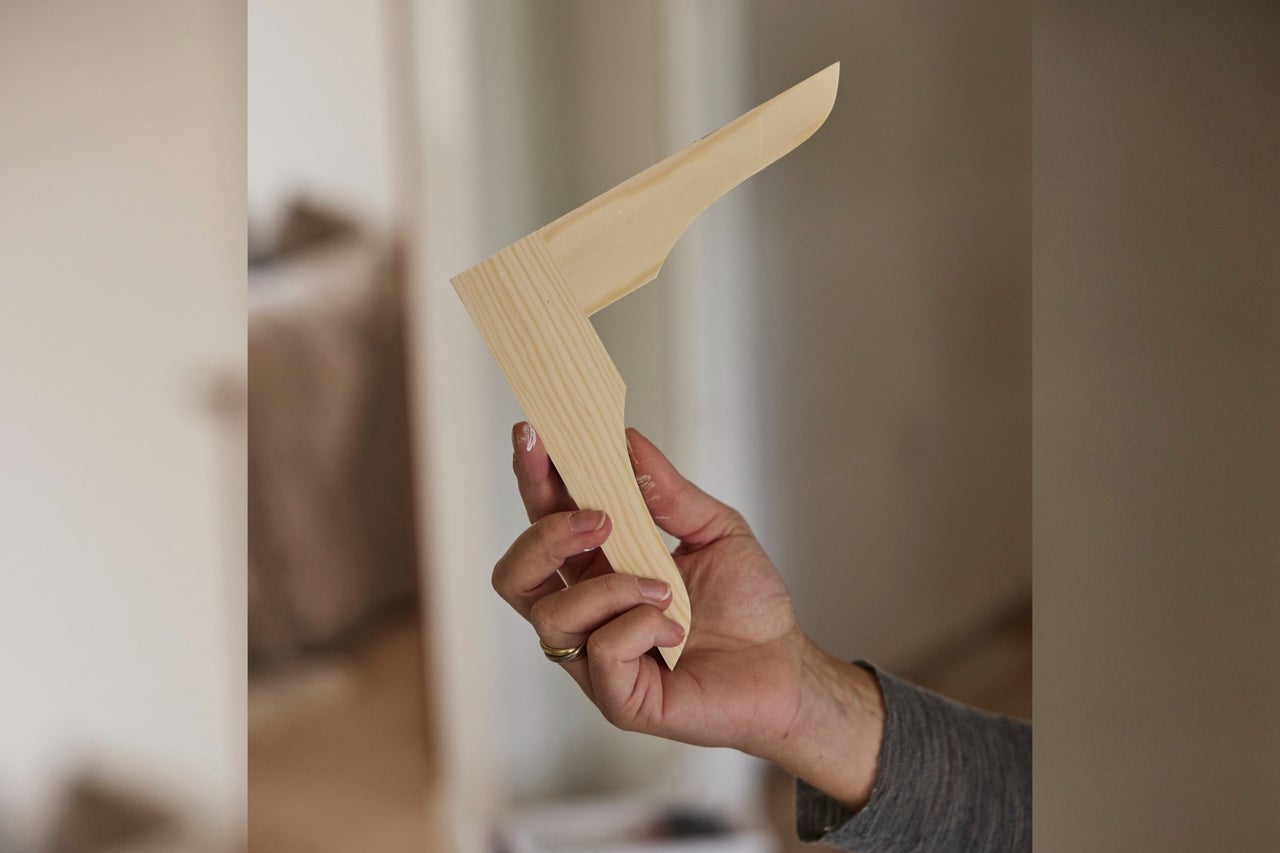 En hand som håller en formad träprofil av ljust furu.