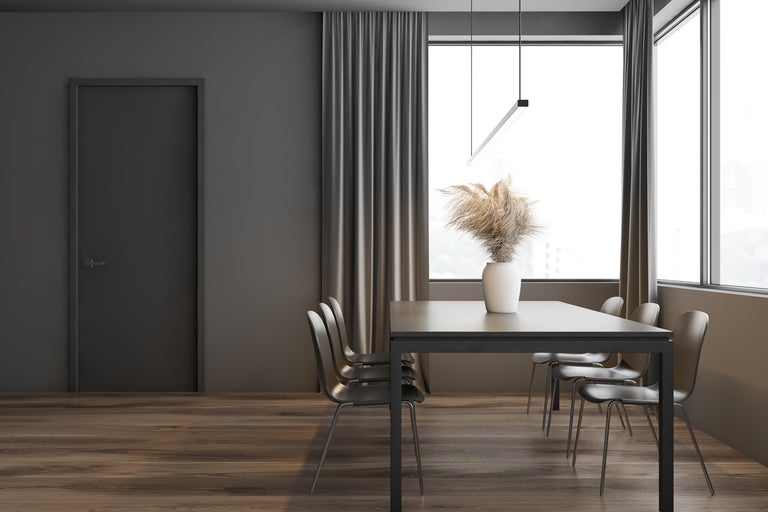 Interiörbild av en matsal med bord, stolar och gardiner