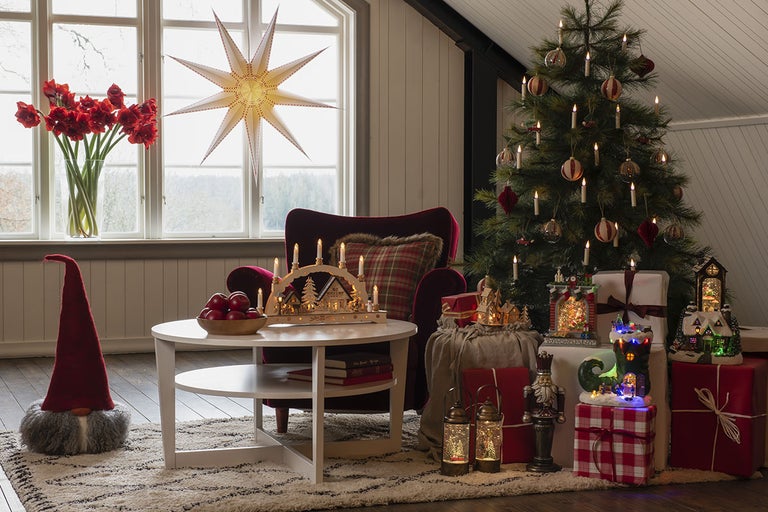 Juldekorerat rum med julgran, presentpaket, adventsljusstake, stjärna och blombukett