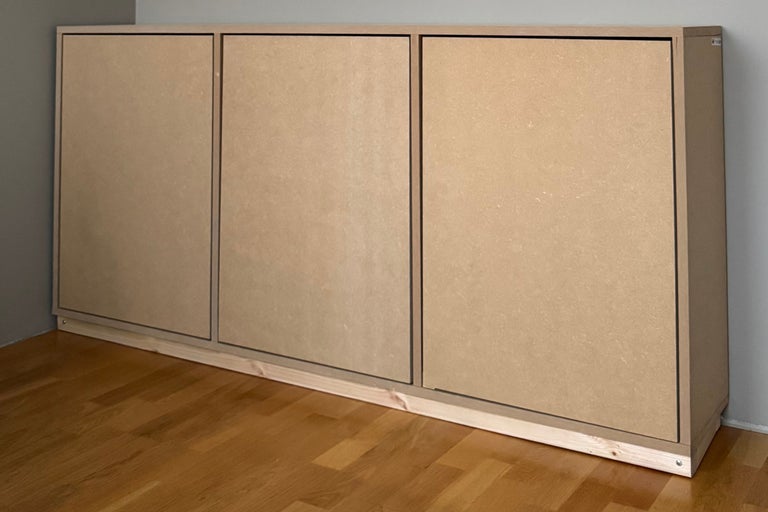 Väggskåp i MDF med tre dörrar och träsockel på trägolv