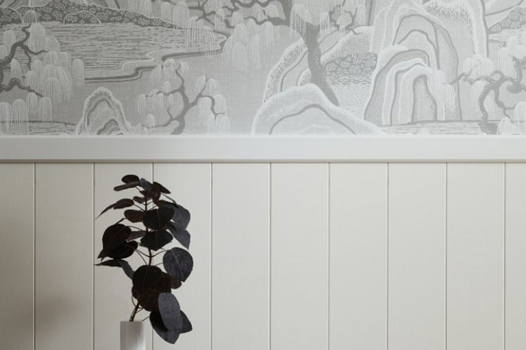 Väggdekoration med mönstrad tapet och paneler.