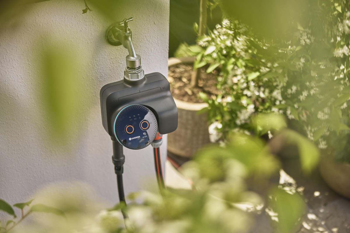 Gardena smart bevattningsdator monterad på en utomhuskran i trädgården för automatisk bevattning.