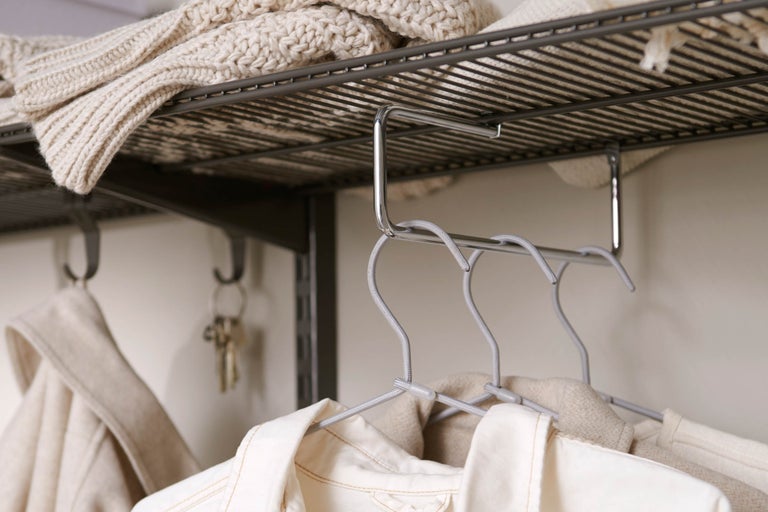 Garderob med kläder på galgar och en hylla med stickat