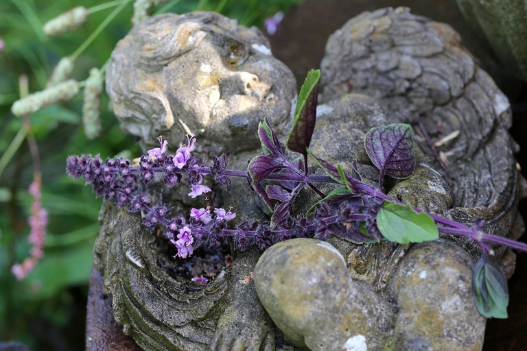 Skulptur av en liggande ängel med lila blommande gren