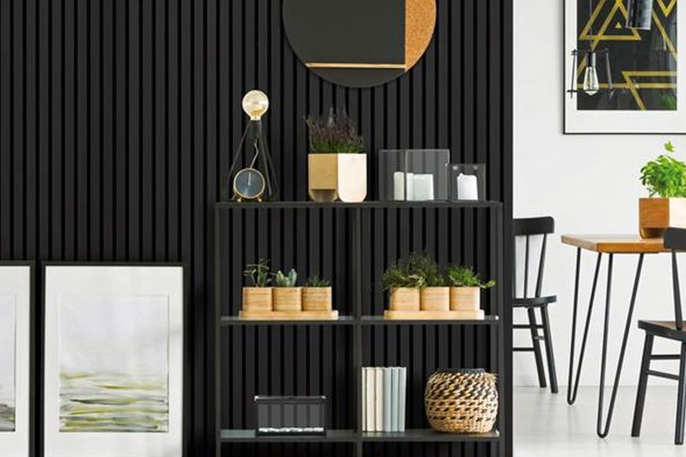Dekorativt vardagsrum med svart bokhylla, bord och stolar.