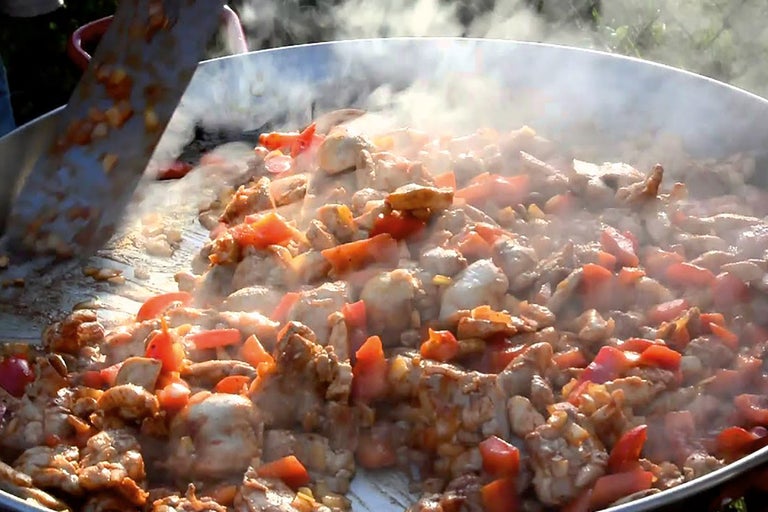Kycklingkött med grönsaker kokas i en paellapanna