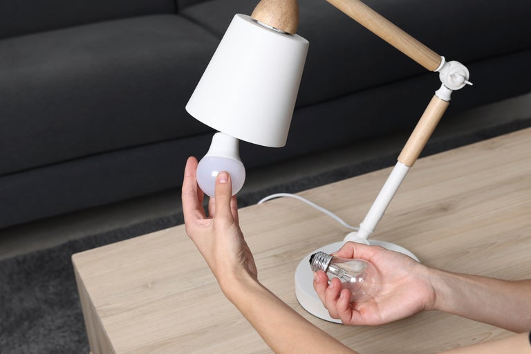 Person byter en glödlampa i en skrivbordslampa