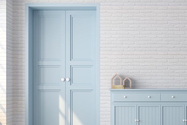 Rumsinteriör med blå dubbeldörr och skänk framför en tegelvägg